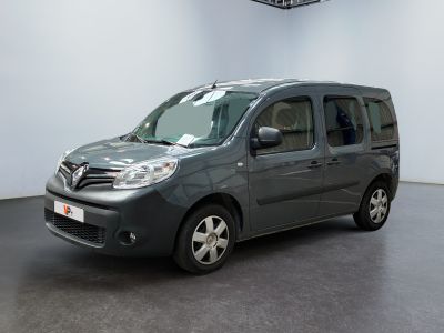 La camionnette grise est garée dans une grande pièce au sol noir.