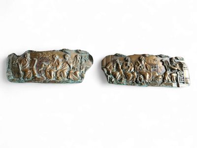 two bronze sculptures of people and animals on a white surface