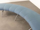 a blue curved bench with metal legs on a concrete floor