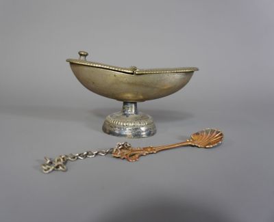 un plateau en argent ancien avec une cuillère et un repose-cuillère posé sur une table