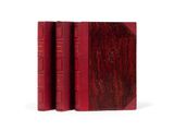 three red books sitting on top of each other on a white surface