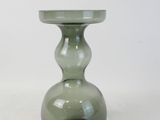 un vase en verre vert avec un socle noir sur fond blanc