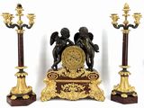 trois statues de chérubins et une horloge posée sur un socle