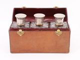 three shot glasses in a wooden case on a white background