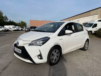 une Toyota Yaris blanche garée sur un parking à côté d'un immeuble