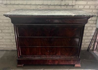 a wooden dresser with marble top in front of a brick wall