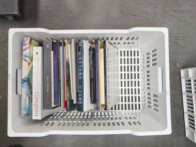 a white basket with books in it on the floor