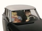 two figurines of people in a car with a steering wheel