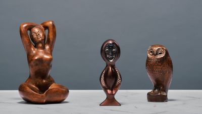trois statues en bronze représentant une femme et un hibou, posées sur une table