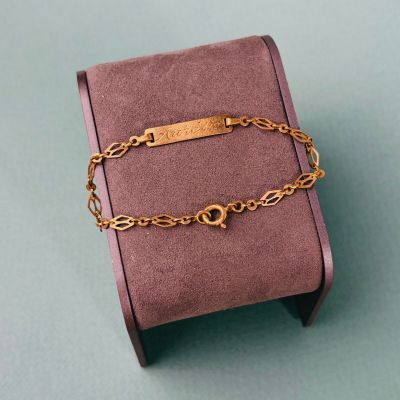 bracelet plaqué or posé dans une boîte rose sur un fond vert