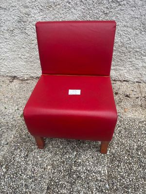 une chaise rouge posée devant un mur sur lequel est accrochée une étiquette