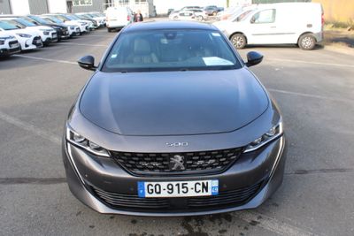 a black car parked in a parking lot with other cars in the background