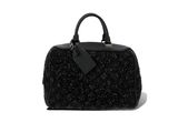 un sac à main noir posé sur une surface blanche
