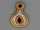 un gros plan sur un pendentif en or orné d'un rubis et d'un diamant en forme de larme