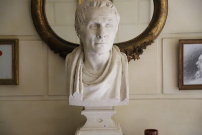 un buste en marbre représentant un homme, posé sur une table devant un miroir