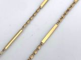a close up of two gold chains on a white surface