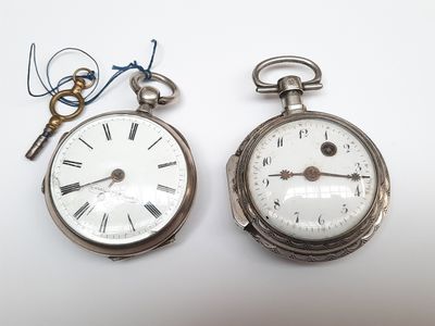 deux montres de poche en argent posées l'une à côté de l'autre sur une table