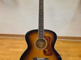a close up of a guitar on a stand on a hard wood floor