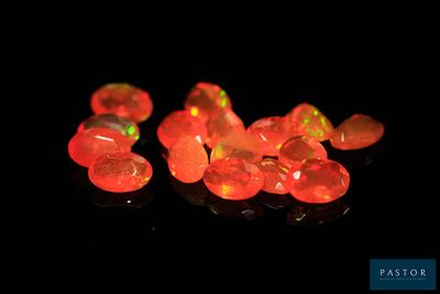 plusieurs morceaux d’oplite rouge « feu » posés sur une surface noire