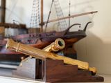 une petite maquette de bateau et un télescope posés sur une étagère