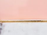 un gros plan d'un collier plaqué or posé sur une surface en marbre