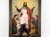 woman walking past a large painting of jesus in a white room