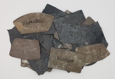 plusieurs morceaux de pierre portant des noms, posés sur une surface blanche