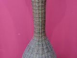 a wicker vase sitting on the floor in front of a pink wall