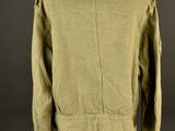 a green jacket on a mannequin stand against a black background