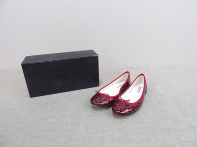 une paire de chaussures rouges posée à côté d'une boîte noire sur une table