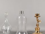 trois vases en verre et un bougeoir en laiton posés sur une table