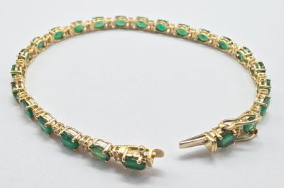 un gros plan d'un bracelet orné de pierres vertes sur un fond blanc