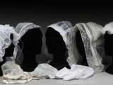 trois mannequins noirs dont la tête est recouverte de dentelle blanche