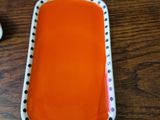an orange plate with polka dots on it next to a cup of coffee