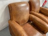 fauteuil inclinable en cuir marron avec accoudoirs, adossé à un mur blanc
