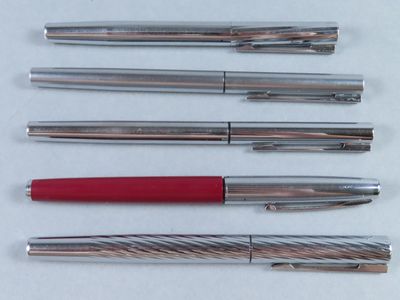 Plusieurs types de stylos sont alignés sur une surface blanche