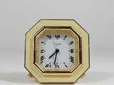 a small gold clock with roman numerals on it