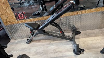 a black bench in a gym with a mirror in the background