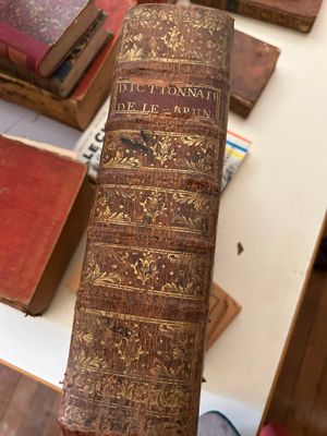 une personne tenant un livre sur une table où se trouvent de nombreux livres