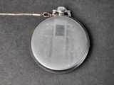 a silver pocket watch with a chain on a table