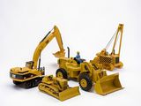 trois engins de chantier miniatures et un bulldozer sur fond blanc