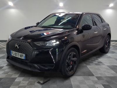 une voiture noire garée dans un garage au sol en damier