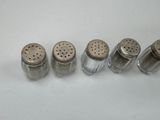 four salt and pepper shakers lined up on a white surface