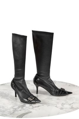 des bottes à talons hauts en cuir noir posées sur une surface en marbre