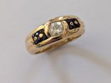 un gros plan d'une bague en or sertie d'un diamant blanc et de diamants noirs