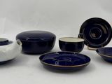 five bowls and a pitcher on a white table