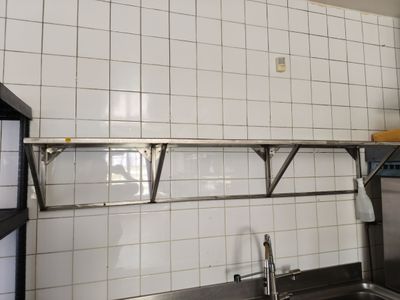 a kitchen with a sink and a metal shelf above the sink