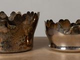 two silver cups sitting on a table next to each other