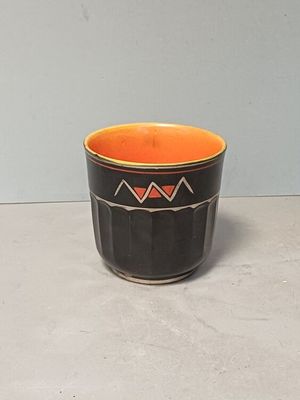 une tasse noire et orange posée sur une table