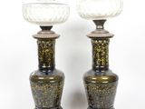 une paire de vases noirs et dorés sur des socles, sur fond blanc